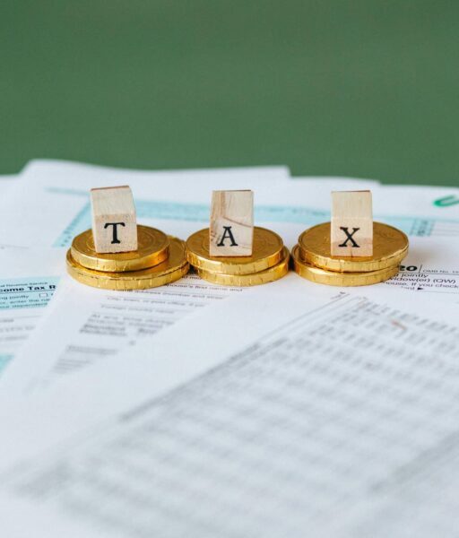 Staged image of gold coins with tax letter tiles on documents.